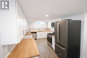 Prince Edward County (Picton Ward) duplex for rent - A kitchen with a black fridge and white cabinets.