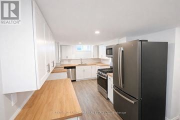 Prince Edward County (Picton Ward) duplex for rent - A kitchen with a black fridge and white cabinets.