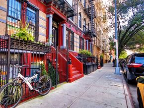 New York apartment for rent - a bicycle parked on a sidewalk in front of a red building
