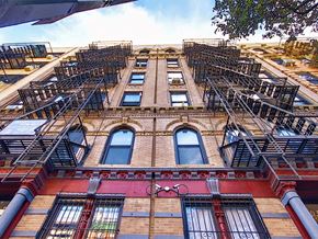 New York apartment for rent - a tall building with fire escapes on the side of it