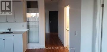 Brantford condo for rent - A hallway with a door on the right and a sink in the kitchen area.