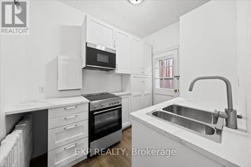 Ottawa multi-family for rent - A white kitchen with a sink and a microwave.