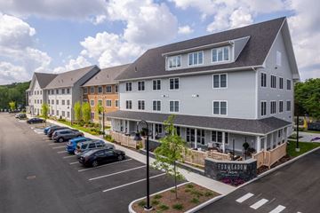 Foxboro apartment for rent - A large white building with a grey roof and a parking lot in front.