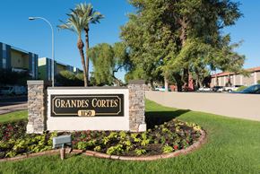 Tempe apartment for rent - a sign for grande condos in front of a street with palm trees