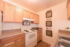 Tucson apartment for rent - a kitchen with white appliances and wooden cabinets
