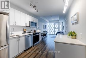 Oshawa (O'neill) condo for rent - A modern kitchen with white cabinets and stainless steel appliances.