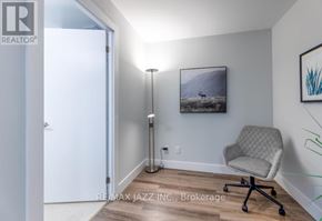 Oshawa (O'neill) condo for rent - A room with a chair and a painting of a mountain scene on the wall.