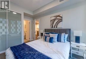 Oshawa (O'neill) condo for rent - A bedroom with a bed, nightstand, and lamp.