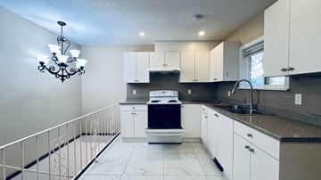 Surrey house for rent - A kitchen with white cabinets and a black fridge.