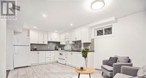 Ottawa house for rent - A well-lit kitchen with white appliances and a dining area with a grey couch and a wooden table.
