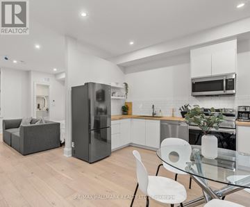 Toronto (Greenwood-Coxwell) other for rent - A modern kitchen with a glass table and white chairs.