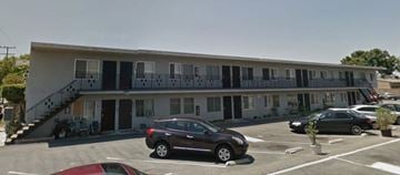Bellflower apartment for rent - A building with a balcony and a car parked in front.