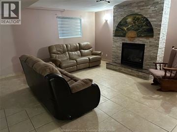 Windsor house for rent - A living room with a stone fireplace and a painting above it.