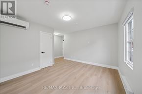 Oshawa (Central) multi-family for rent - A room with a wooden floor and white walls, with a door on the left and a window on the right.