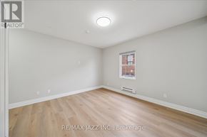 Oshawa (Central) multi-family for rent - A spacious room with a window and wooden flooring.