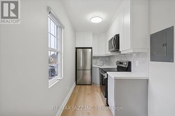 Oshawa (Central) multi-family for rent - A kitchen with white cabinets and a stainless steel refrigerator.