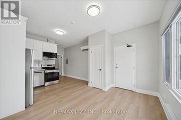 Oshawa (Central) multi-family for rent - A spacious kitchen with white cabinets and a wooden floor.