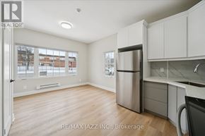 Oshawa (Central) multi-family for rent - A kitchen with white cabinets and a refrigerator in a room with a window.