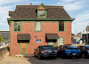 Ann Arbor apartment for rent - A red brick building with a green roof and a car parked in front.