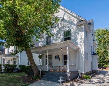 Ann Arbor apartment for rent - A white house with a porch and a tree in front.