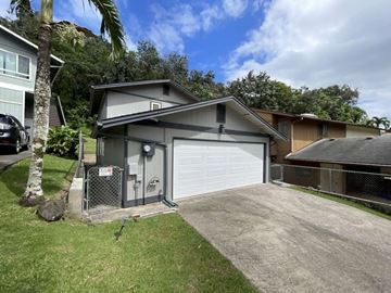 Kaneohe apartment for rent - A detached garage with a white door is surrounded by a fence and a palm tree.