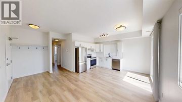 Grande Prairie other for rent - A spacious kitchen with a refrigerator, sink, and cabinets is visible in the image.