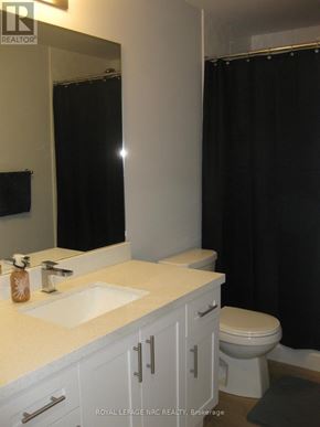 Niagara Falls (Morrison) condo for rent - A white bathroom with a sink, toilet and black shower curtain.