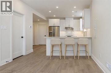 Guelph/Eramosa house for rent - A modern kitchen with white cabinets and a bar area.