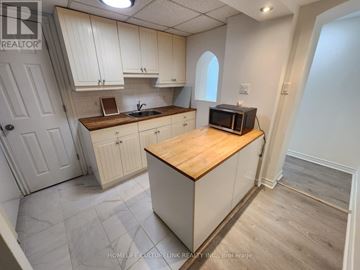 Toronto (Bendale) house for rent - A kitchen with white cabinets and a wooden island.