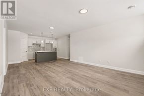 For rent in Russell - A room with a wooden floor and white walls, with a kitchen area visible in the background.