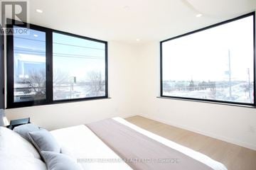 Toronto (Alderwood) townhouse for rent - A bedroom with a large bed and two windows.