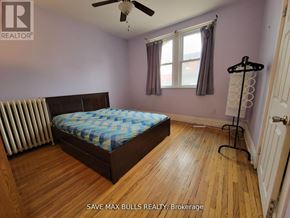 Hamilton (Central) condo for rent - A bedroom with a bed, a ceiling fan, and a window.