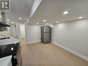 Toronto (South Riverdale) house for rent - A kitchen with a stainless steel refrigerator and wooden flooring.