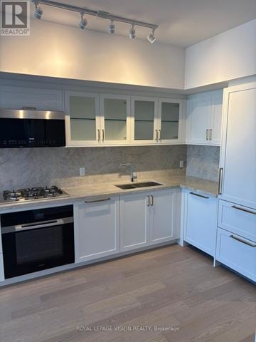 Toronto (Englemount-Lawrence) condo for rent - A kitchen with white cabinets and a black stove top.