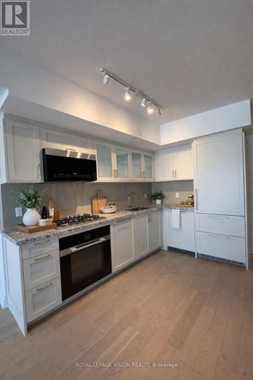 Toronto (Englemount-Lawrence) condo for rent - A modern kitchen with white cabinets and appliances.