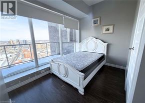 Waterloo condo for rent - A bedroom with a large bed and a view of the city.