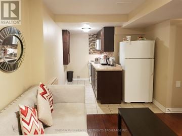 Brampton (Fletcher's Creek Village) house for rent - A kitchen with a white refrigerator and a couch with red and white pillows.