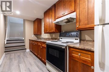 London house for rent - A kitchen with wooden cabinets and a black stove top oven.