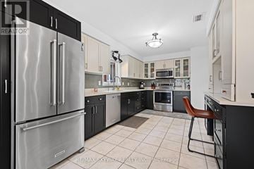 Guelph (Grange Road) house for rent - A modern kitchen with a stainless steel refrigerator and a tiled floor.