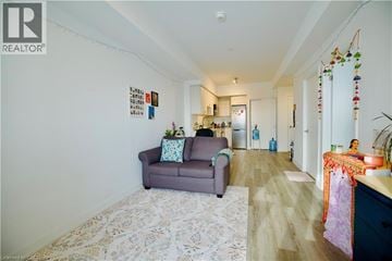 Kitchener condo for rent - A living room with a grey couch and a patterned rug.