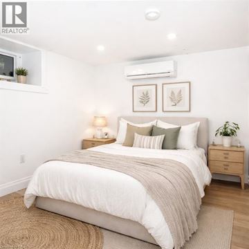 Hamilton apartment for rent - A bedroom with a large bed, a nightstand with a lamp, and two framed leaves on the wall.