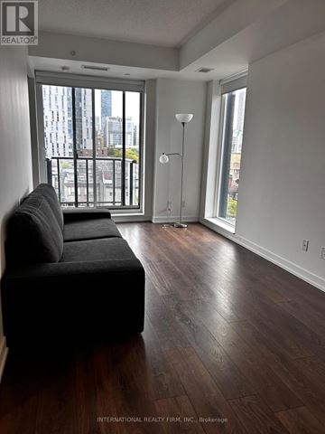 Toronto (Kensington-Chinatown) condo for rent - A living room with a black couch and a view of the city.