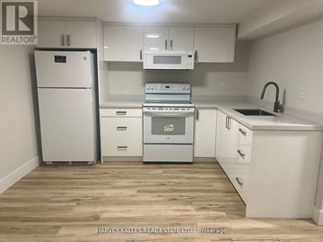 Toronto (Clanton Park) house for rent - A kitchen with white appliances and cabinets.