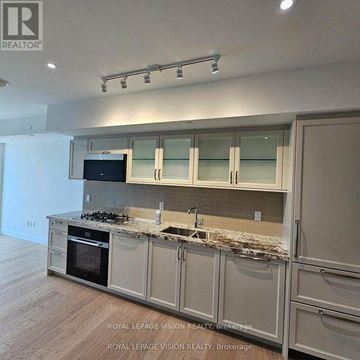 Toronto (Englemount-Lawrence) condo for rent - A modern kitchen with a stove top oven and a microwave above the stove.