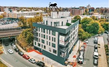 Brooklyn apartment for rent - A building with a bull statue on top and cars parked in front.
