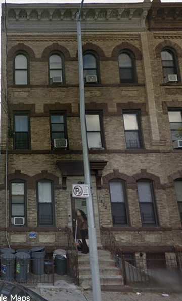 Ridgewood apartment for rent - A woman is walking down the sidewalk in front of a brown building.