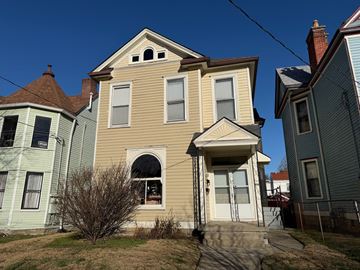 Louisville apartment for rent - A two-story house with a front porch and a small tree in front.