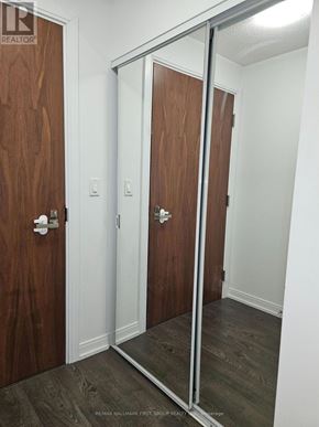 Toronto (Agincourt South-Malvern West) condo for rent - A hallway with a wooden door and a mirror on the wall.
