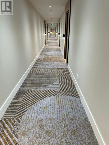 Toronto (Englemount-Lawrence) condo for rent - A long hallway with a carpeted floor and white walls.