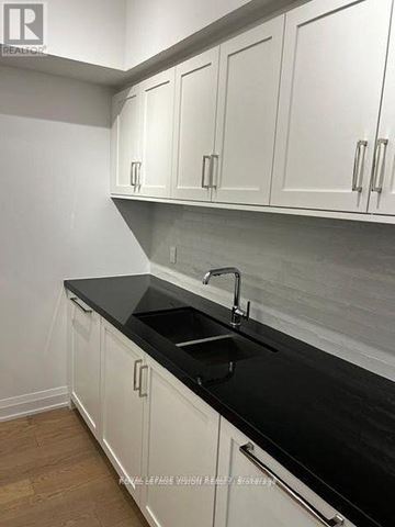 Toronto (Englemount-Lawrence) condo for rent - A kitchen with white cabinets and black countertops.